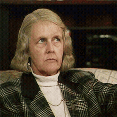 An Older Woman Wearing A Plaid Jacket And A White Turtleneck GIF