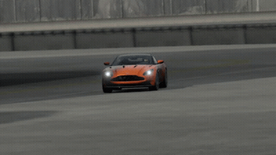 An Orange Aston Martin Sports Car Is Driving On A Track GIF
