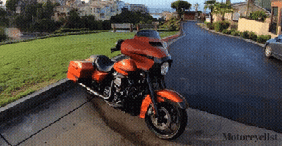 An Orange Harley Davidson Motorcycle Is Parked On The Curb GIF