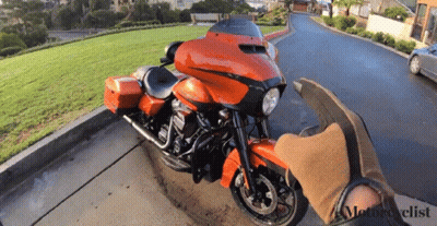 An Orange Harley Davidson Motorcycle Is Parked On The Side Of A Road GIF