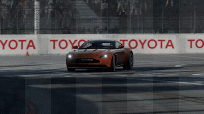 An Orange Sports Car Is Driving On A Race Track With Toyota Signs On The Side GIF