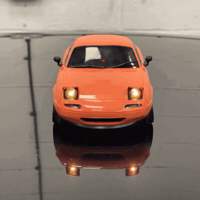 An Orange Toy Car Is Sitting On A Black Table GIF