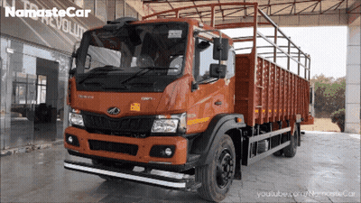 An Orange Truck Is Parked In Front Of A Namaste Car Revolution Store GIF