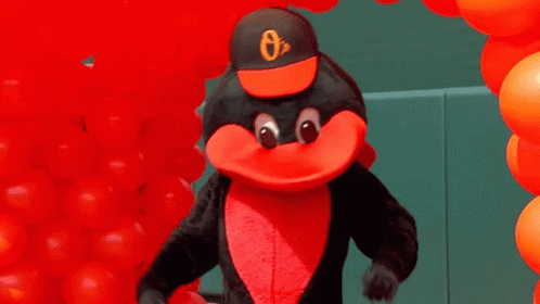 An Orioles Mascot Is Standing In Front Of A Bunch Of Red Balloons GIF
