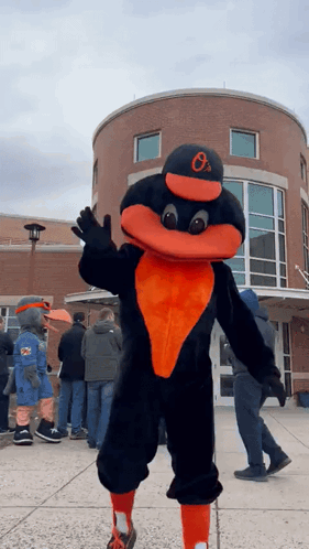 An Orioles Mascot Stands In Front Of A Crowd Of People GIF
