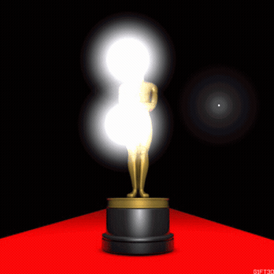 An Oscar Statue Is On A Red Carpet With A Light Behind It GIF