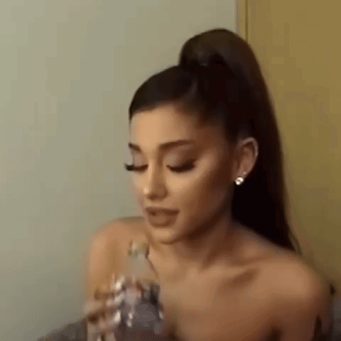 Ariana Grande Is Holding A Bottle Of Water In Her Hand And Drinking It . GIF