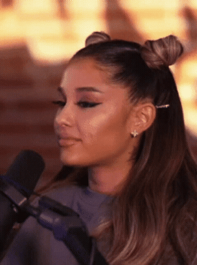 Ariana Grande Is Sitting In Front Of A Microphone With Her Hair In Two Buns . GIF