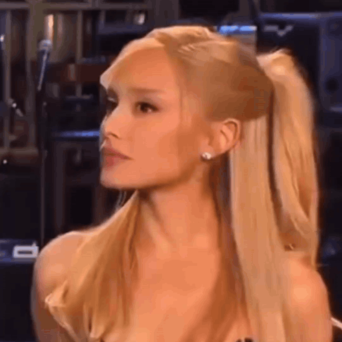 Ariana Grande Is Wearing A Ponytail And Earrings While Sitting In Front Of A Microphone . GIF