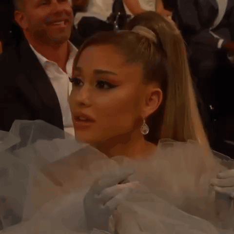 Ariana Grande Is Wearing A White Dress And Earrings While Sitting In A Crowd At Awards . GIF