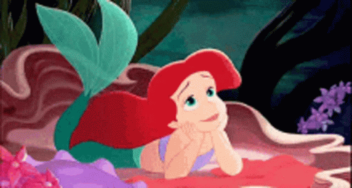 Ariel From The Little Mermaid Is Laying On A Rock GIF