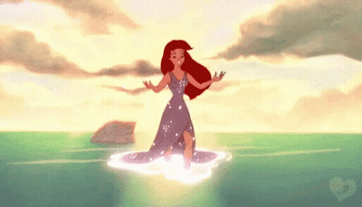 Ariel From The Little Mermaid Is Standing In The Ocean . GIF