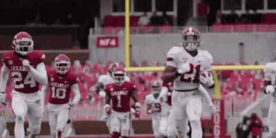 Arkansas Football Players Running On The Field With The Number 21 On Their Jersey GIF