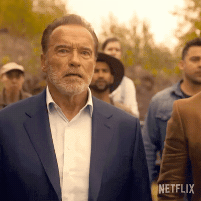 Arnold Schwarzenegger In Blue Suit Standing Before Crowd GIF