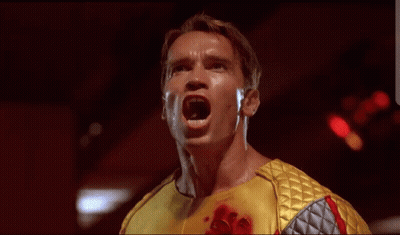 Arnold Schwarzenegger In Yellow And Silver Outfit With Blood GIF