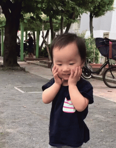 Baby Covering Face With Hands Next To Bicycle GIF
