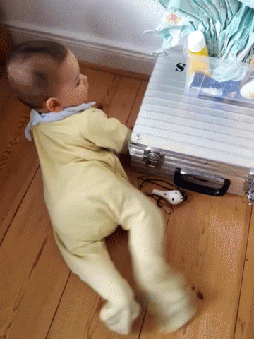 Baby Crawling Next To Briefcase With Letter S GIF
