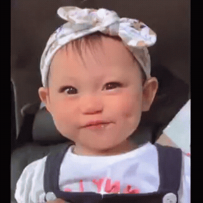 Baby Girl In Headband And Overalls Making Face GIF