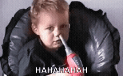 Baby Holding Toy Screwdriver In Nose In High Chair GIF