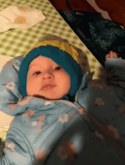 Baby In Blue Hat And Jacket Laying On Bed GIF
