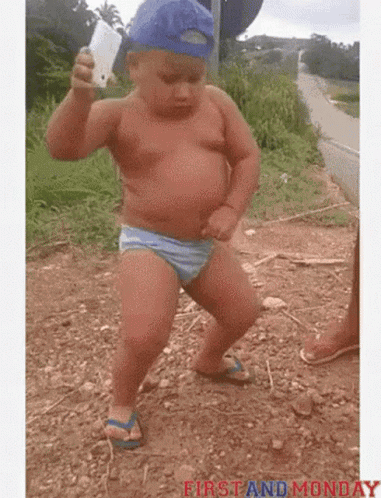 Baby In Blue Hat Dancing In Dirt Holding Cell Phone GIF
