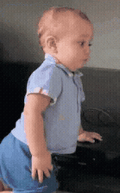 Baby In Blue Outfit By Black Couch GIF