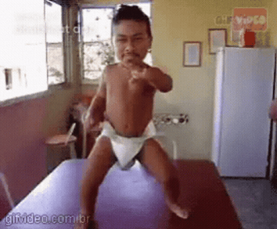 Baby In Diaper Standing On Table Pointing At Camera GIF