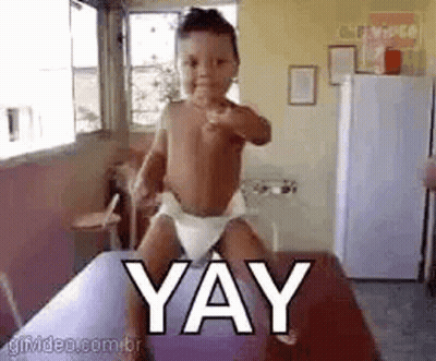 Baby In Diaper Standing On Table With Yay GIF