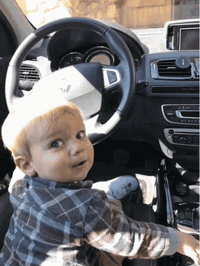 Baby In Driver's Seat Looking At Camera GIF