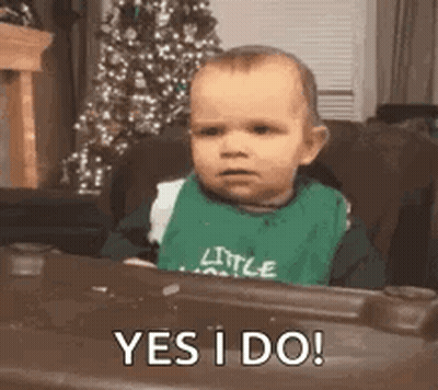 Baby In Green Bib Sitting In Chair GIF