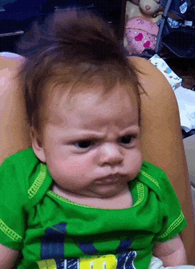 Baby In Green Shirt Making A Face GIF