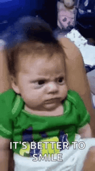 Baby In Green Shirt Making Funny Face GIF
