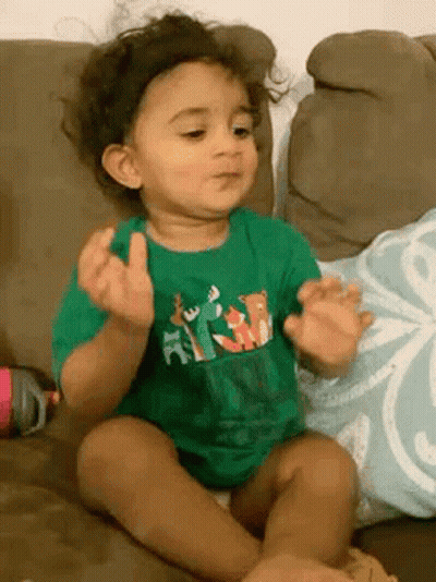 Baby In Green Shirt Making Funny Face GIF