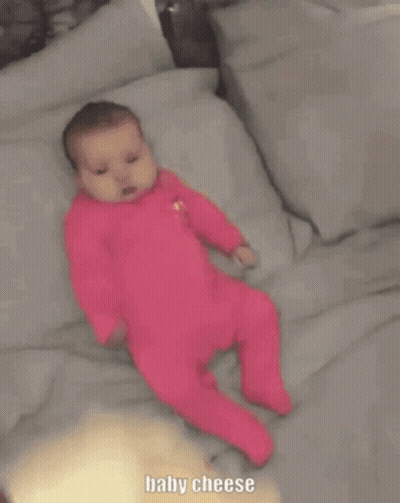 Baby In Pink Outfit Laying On Bed Baby Cheese GIF