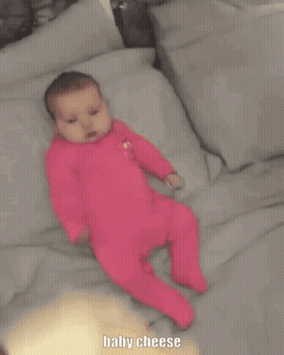 Baby In Pink Outfit Laying On Bed GIF