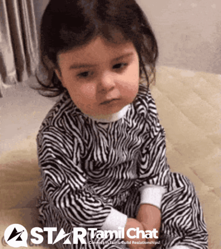 Baby In Zebra Print Pajamas Sitting On Wooden Floor GIF