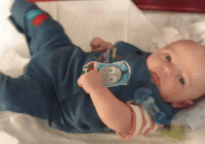 Baby Laying On Bed With Pacifier In Thomas The Tank Engine Shirt GIF