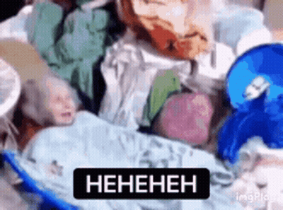 Baby Laying On Pile Of Clothes With Heneheneh Sign GIF