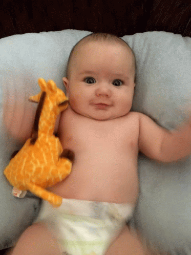 Baby Laying On Pillow With Stuffed Giraffe GIF