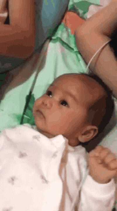 Baby Lying On Bed Held By Woman GIF