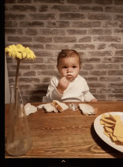Baby Sitting At Table With Food And Flowers GIF