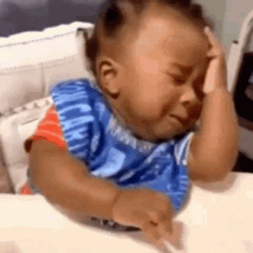 Baby Sitting At Table With Hand On Head GIF