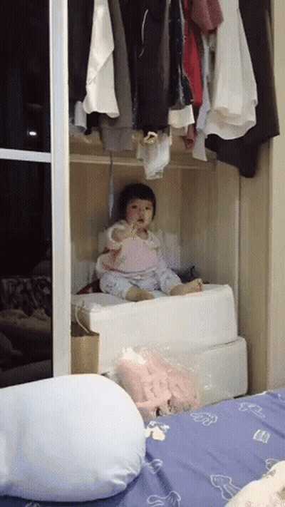 Baby Sitting In Closet Next To Bed And Pillow GIF
