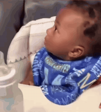 Baby Sitting In High Chair With Bib And Bottle GIF