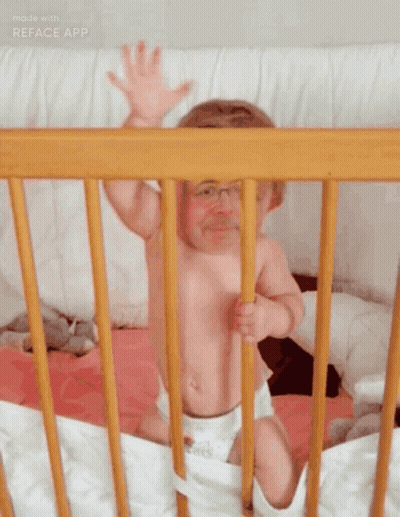 Baby Sitting In Wooden Crib Arms Outstretched GIF