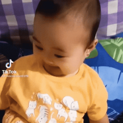 Baby Sitting On Bed In Yellow Elephant Shirt GIF