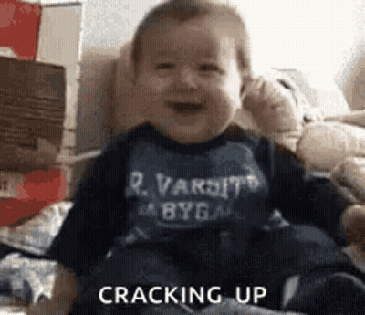 Baby Sitting On Couch Wearing Varsity Shirt GIF