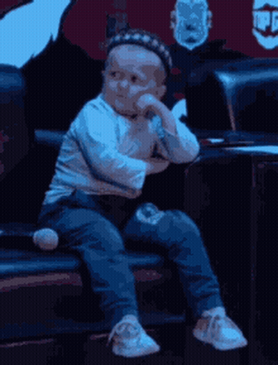 Baby Sitting On Couch With Hat GIF