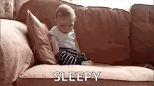 Baby Sitting On Couch With Sleepy GIF