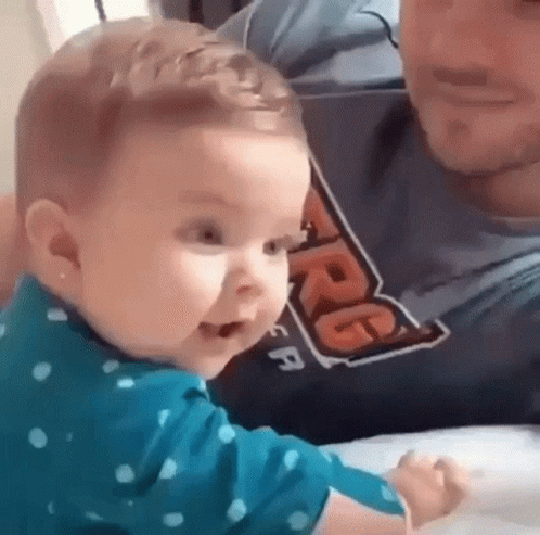 Baby Sitting On Man's Lap Making Funny Face GIF